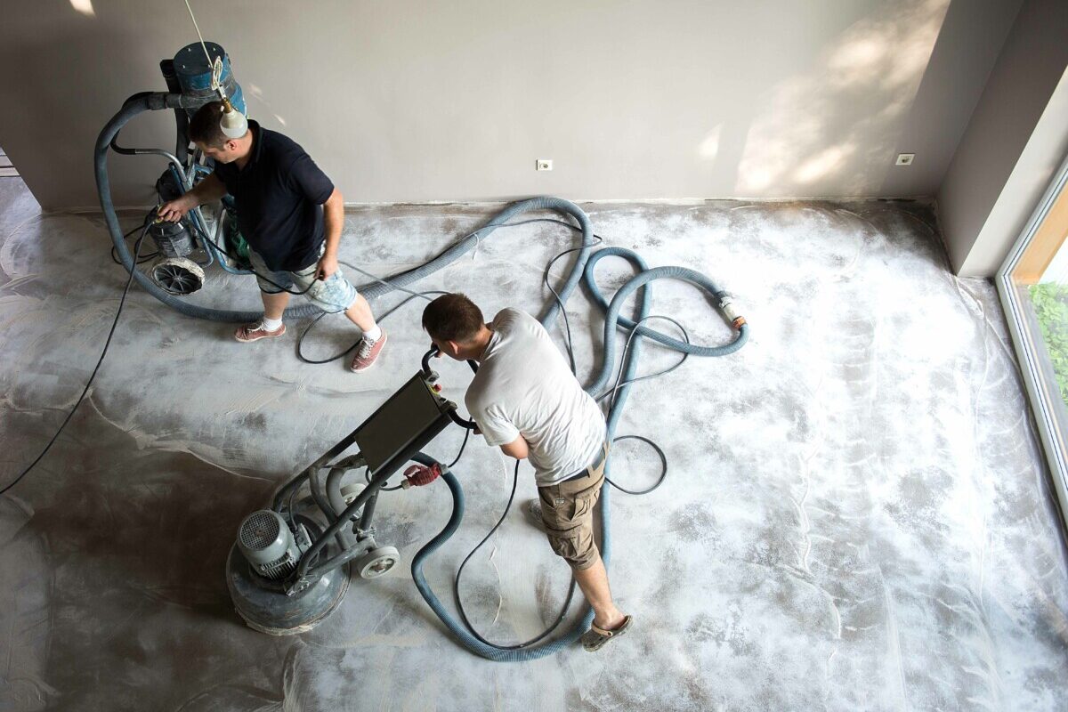 Construction worker in a family home living room that grind the concrete surface before applying epoxy flooring.Polyurethane and epoxy flooring.Concrete grinding.