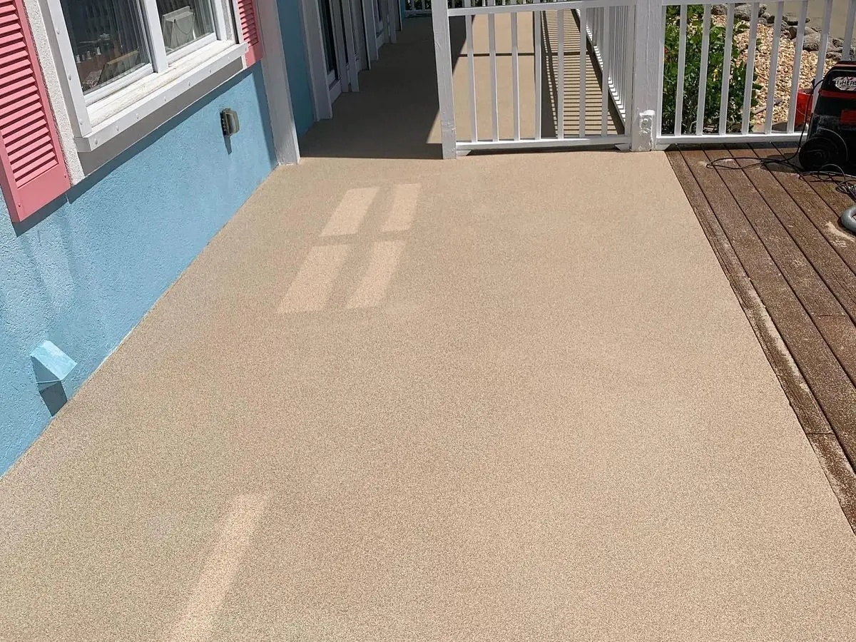 Light flake coating on an outdoor walkway beside a house